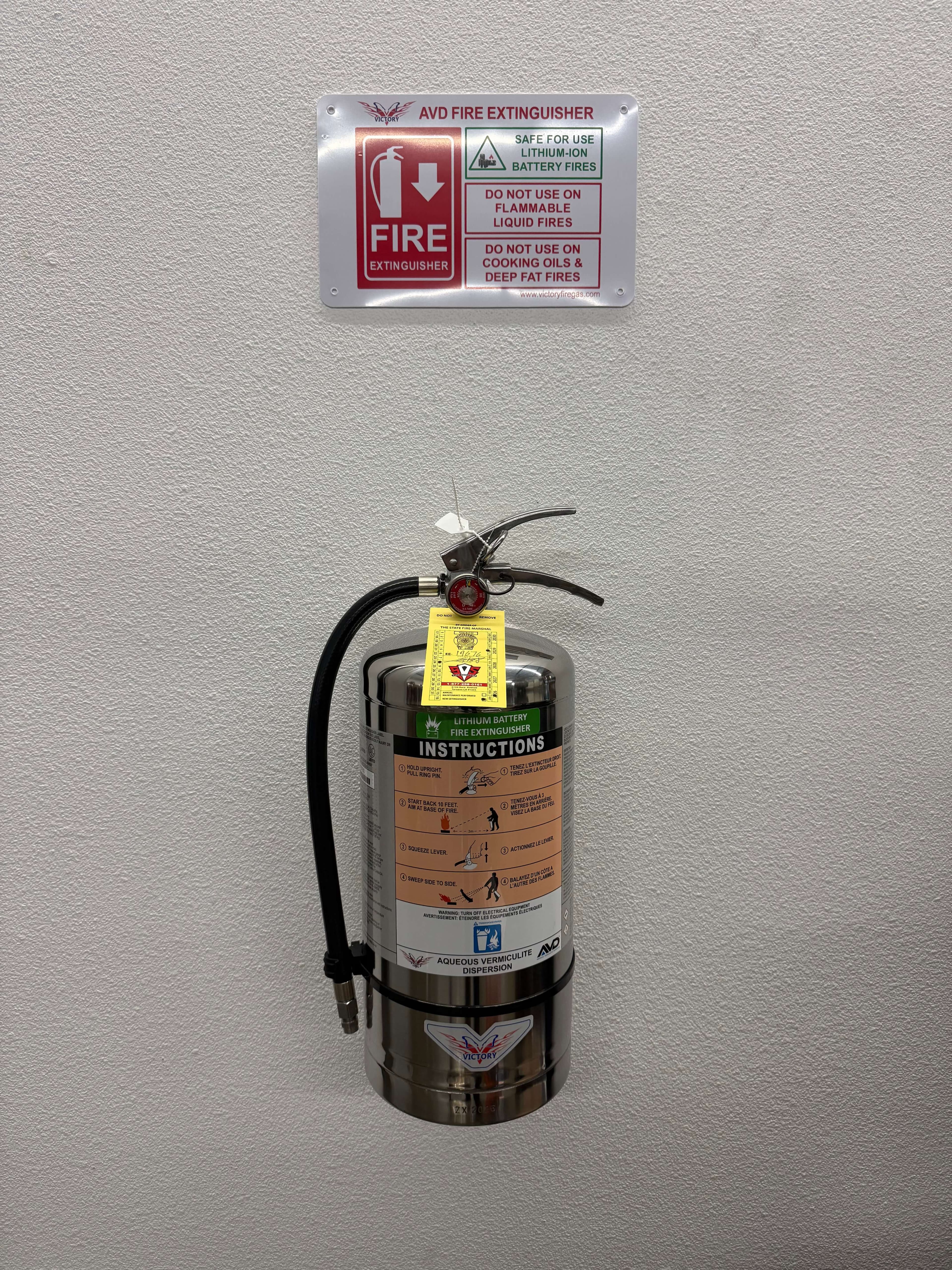 Amerex 5 lb ABC fire extinguisher on a wall bracket with a yellow State Fire Marshal service tag