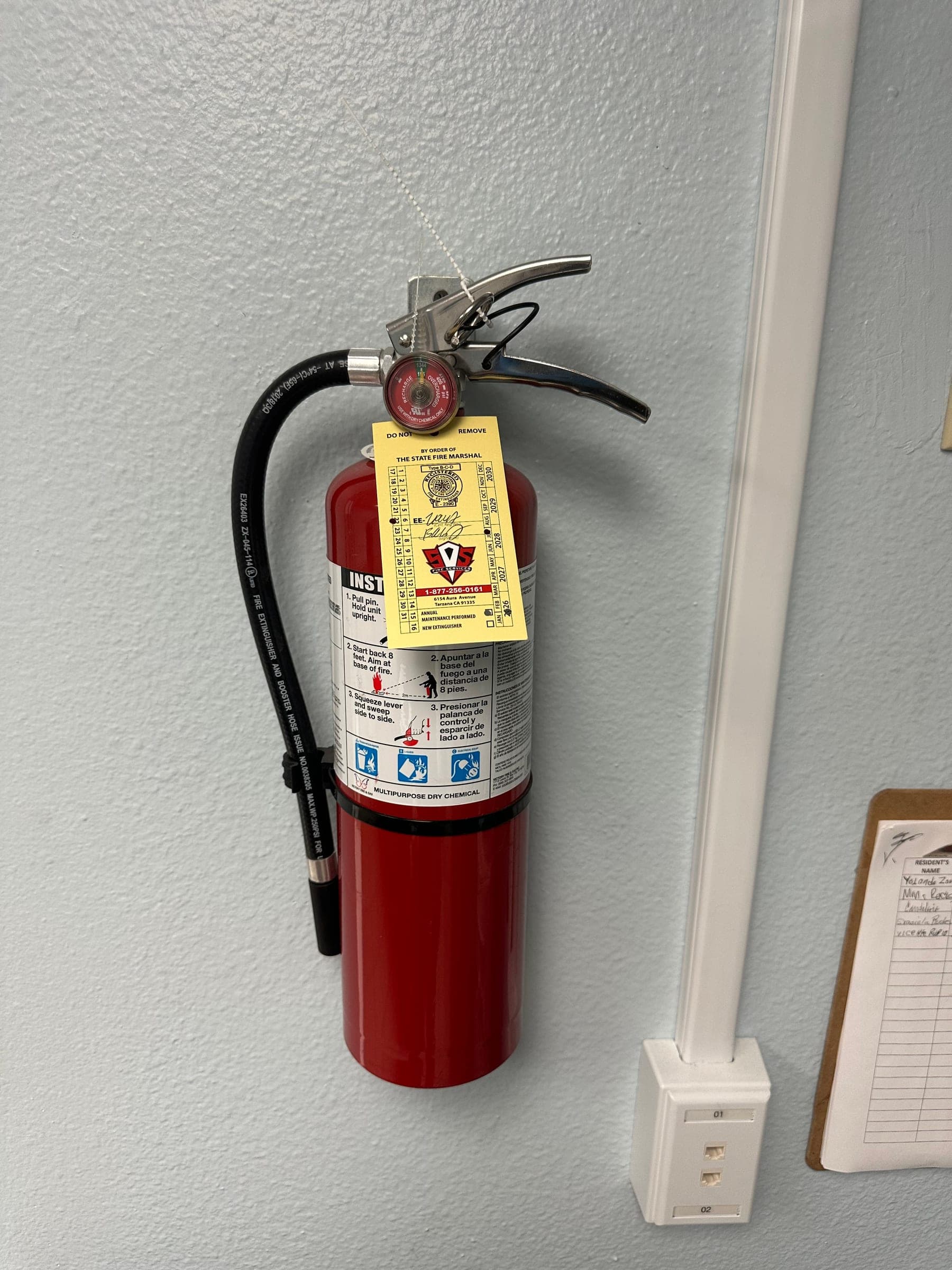 Amerex 5 lb ABC extinguisher on a wall bracket with a yellow State Fire Marshal service tag