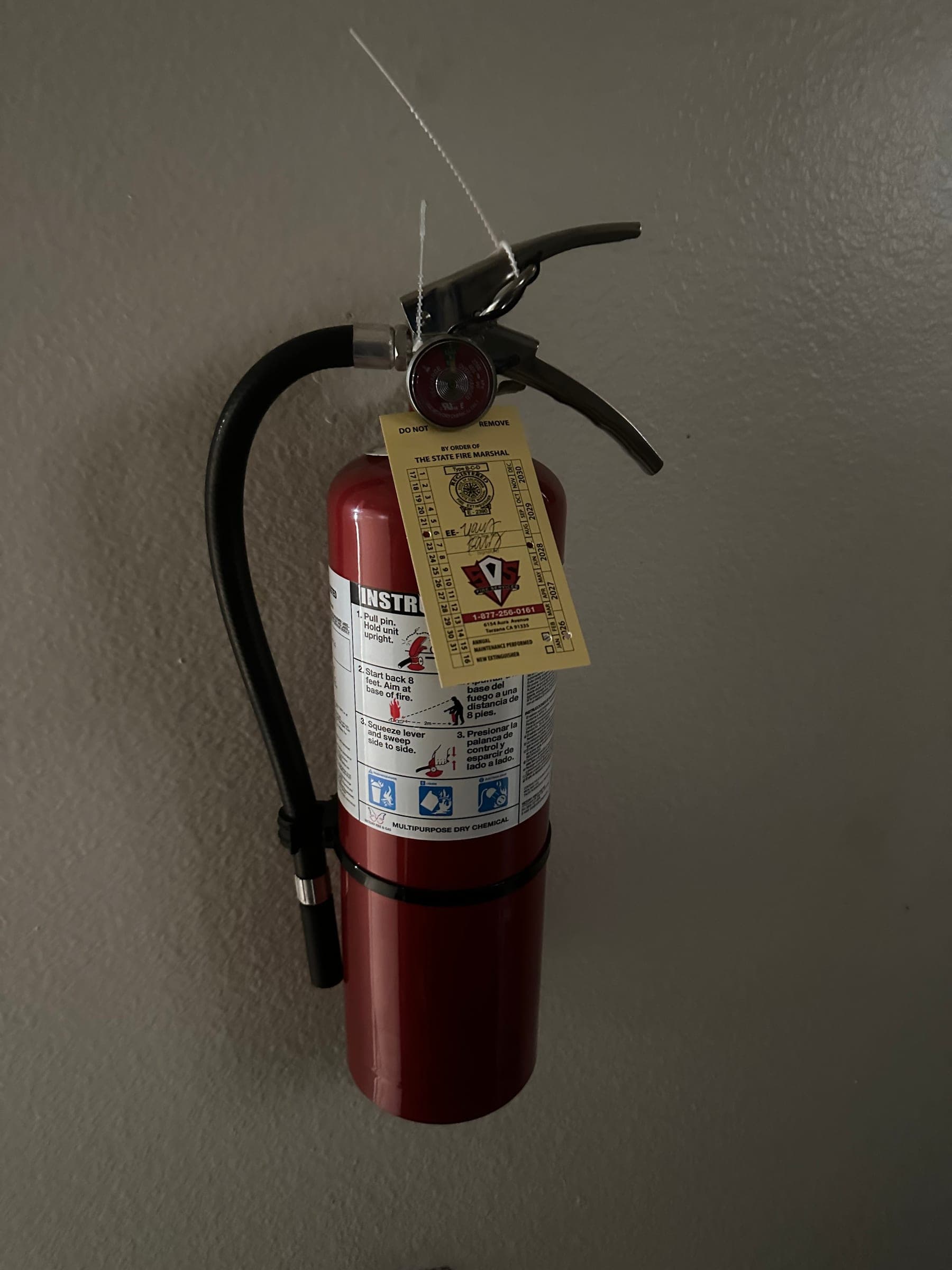 5 lb ABC extinguisher on a wall bracket with its tag and new tamper seal