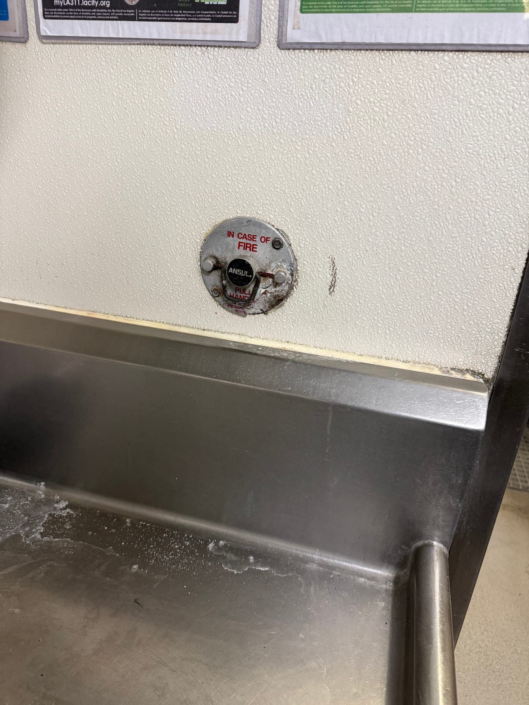 Old Ansul pull station mounted low on the wall above a stainless prep sink