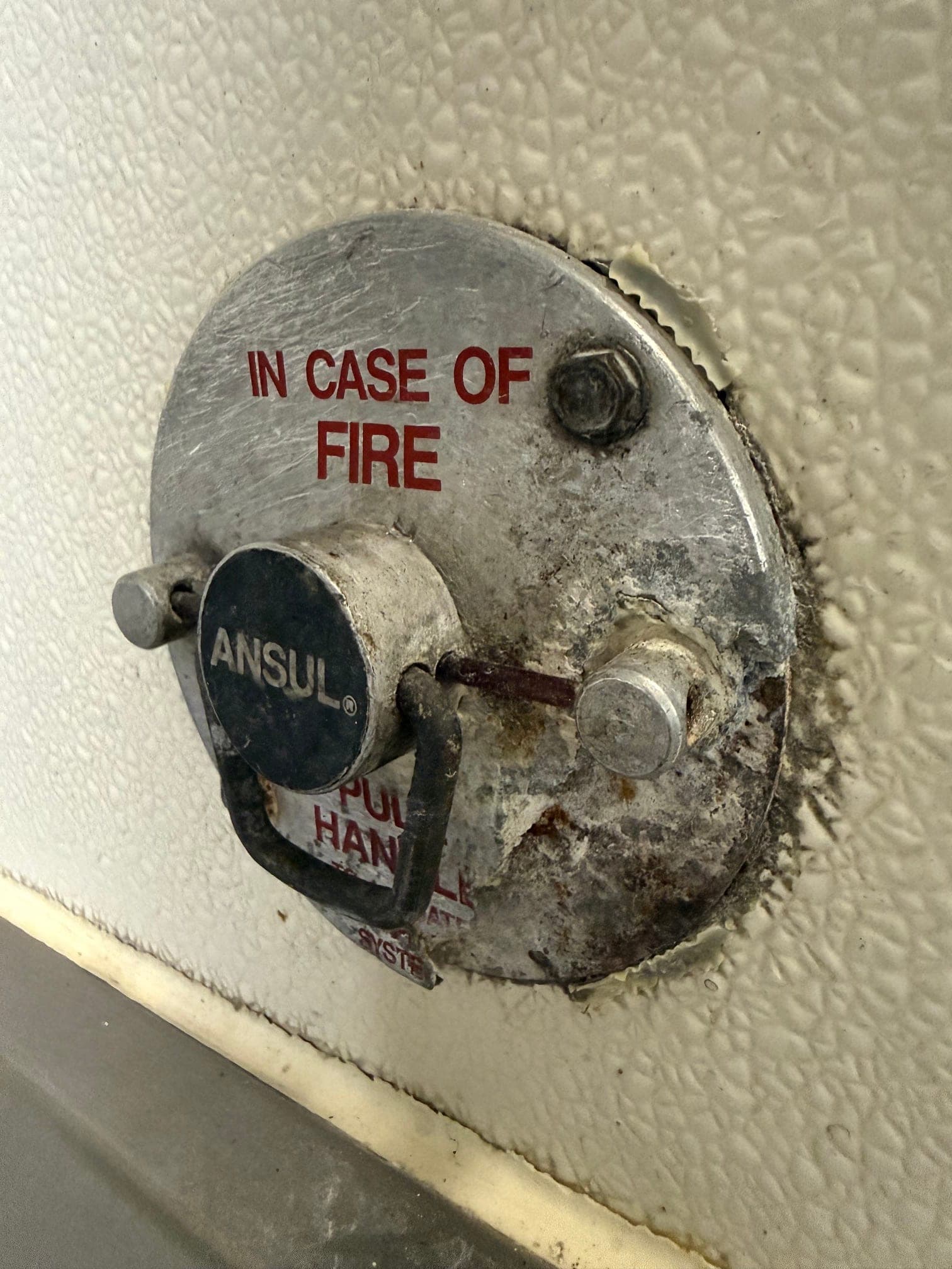 Close-up of the old pull station with a worn handle and oxidized faceplate