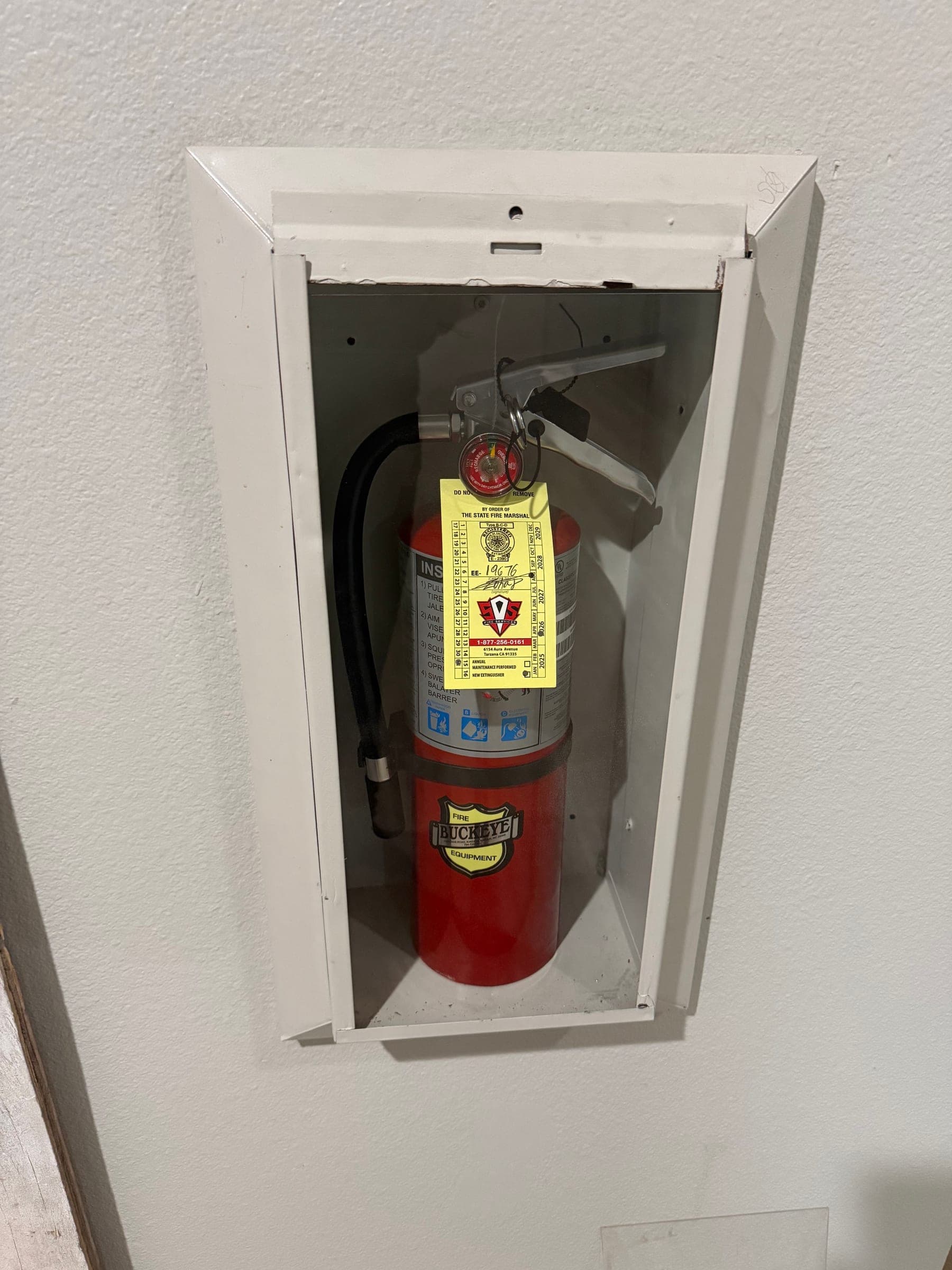 Open-front recessed cabinet with a tagged ABC extinguisher secured by its bracket