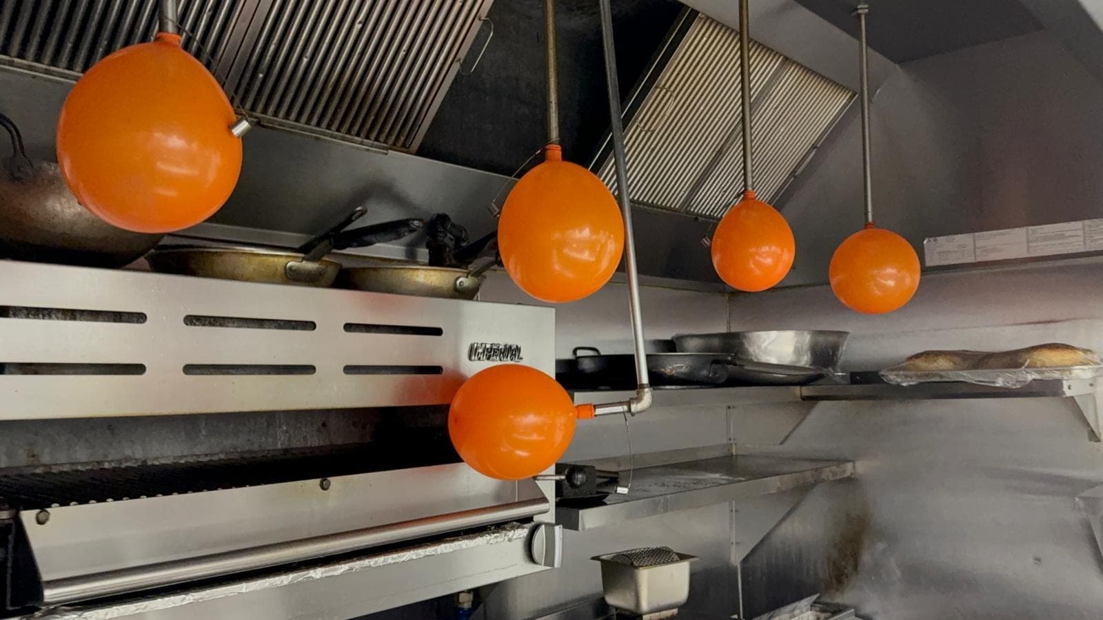 Inflated orange test balloons on the nozzles over a salamander broiler and range, showing an open path to each