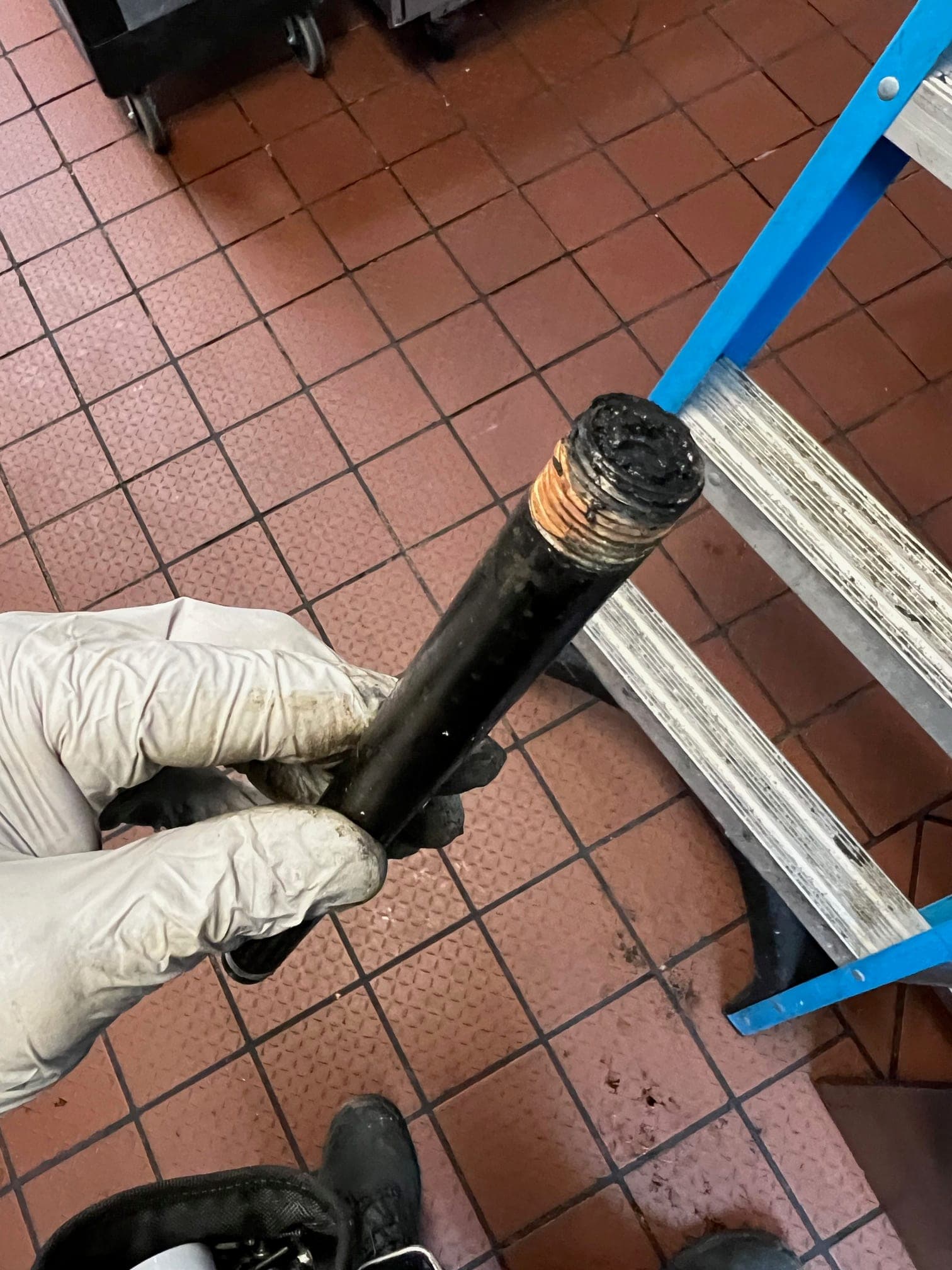 Length of black iron pipe held up to show its end plugged with carbonized grease
