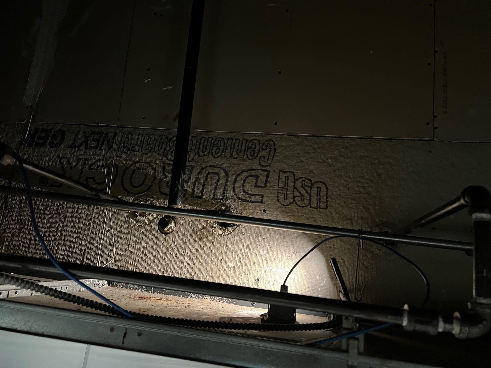 Suppression pipe run along the hood with an elbow down to a nozzle, seen from below