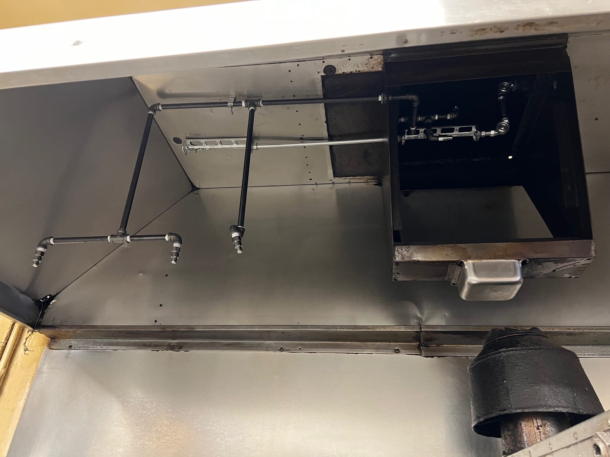 Suppression piping, nozzles and detection line inside an exhaust hood above the plenum
