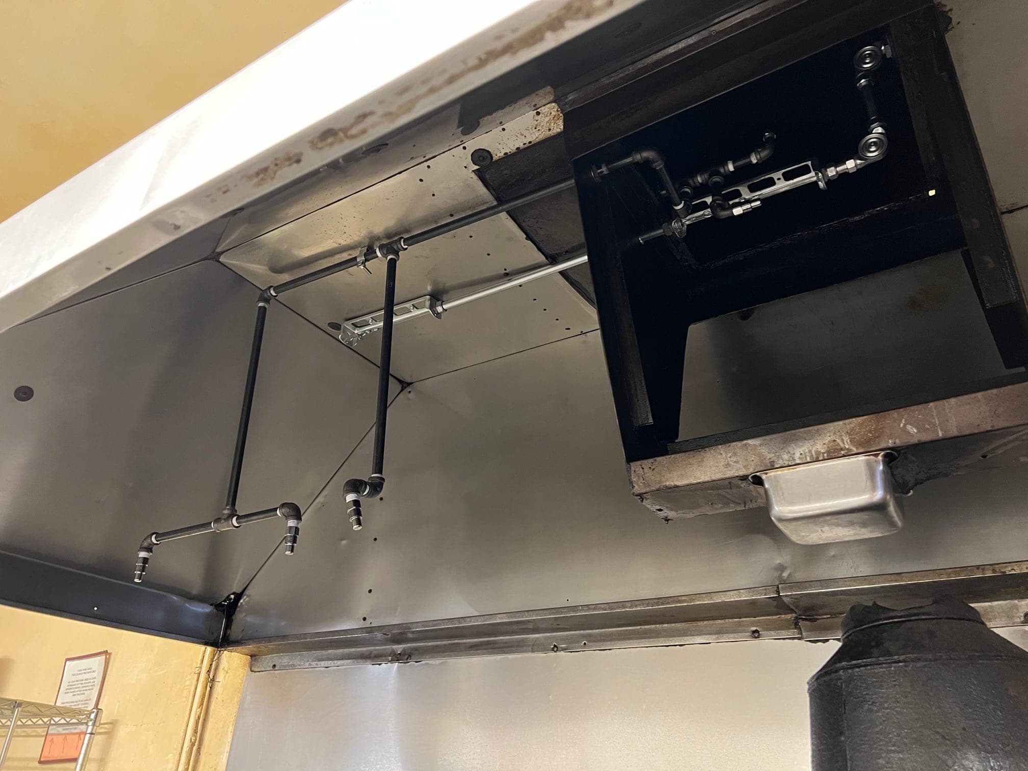 Nozzle drops and plenum piping inside the hood, with the duct collar above