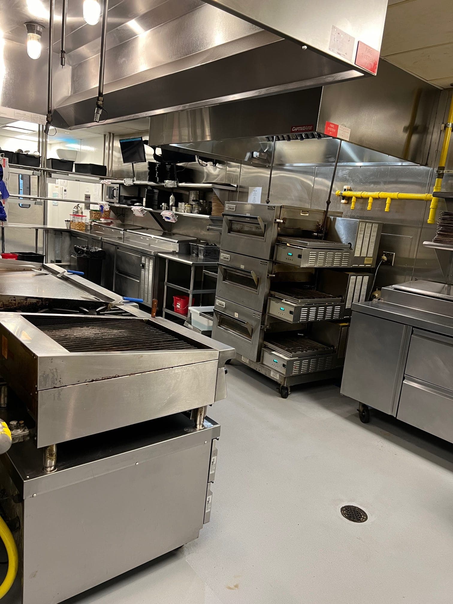 Charbroiler and cooking line beneath the exhaust hoods in the kitchen