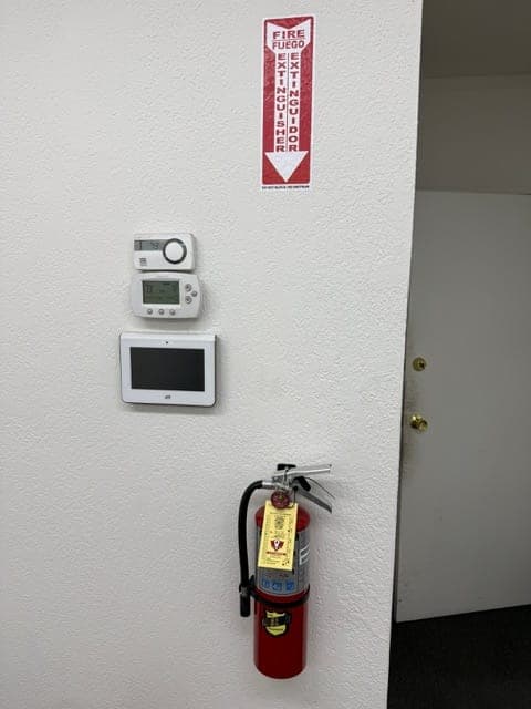 Tagged ABC extinguisher mounted on an office wall below a bilingual extinguisher location sign