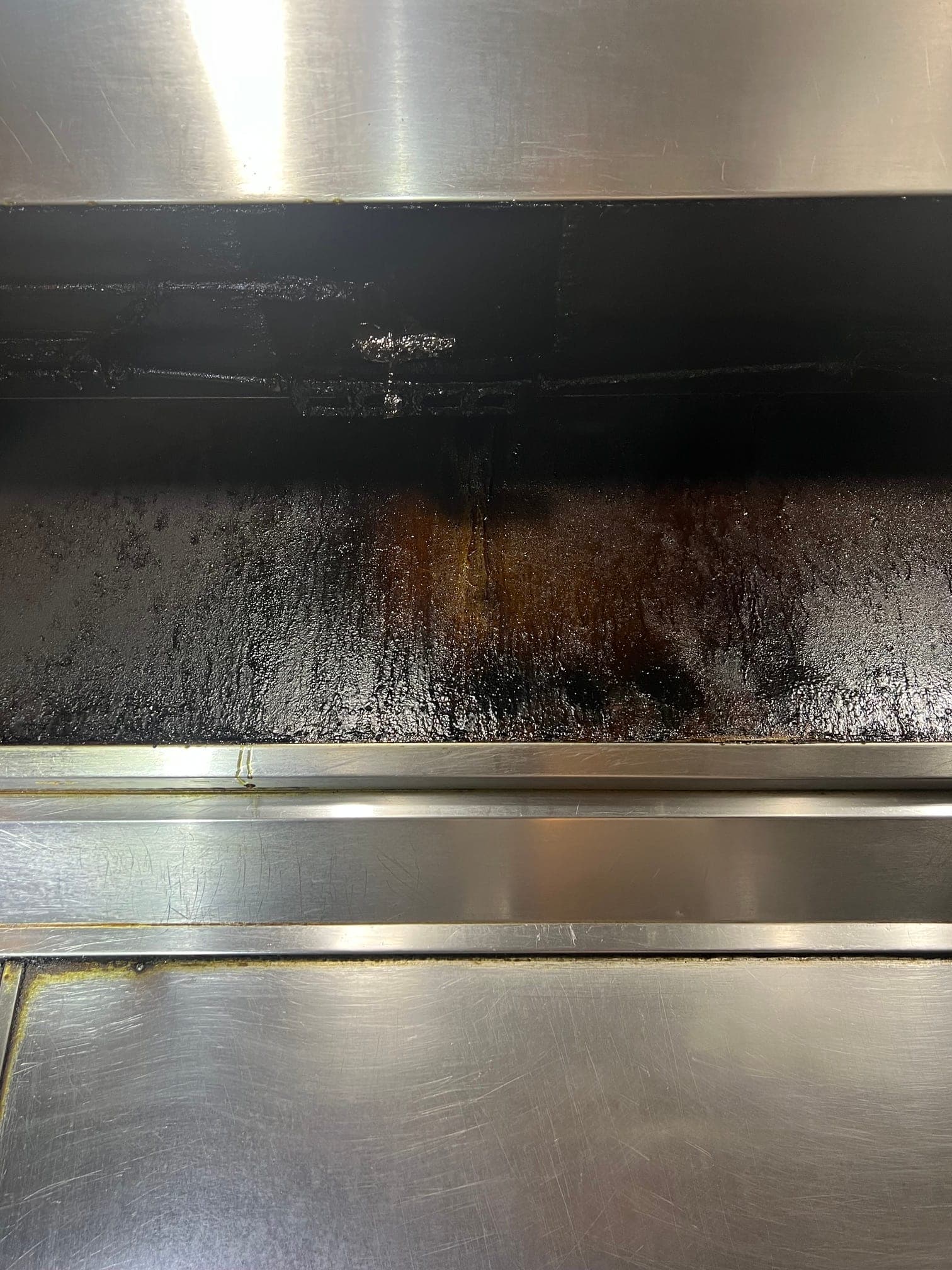 Inside of a wok-line exhaust hood coated in dark grease above the detection line