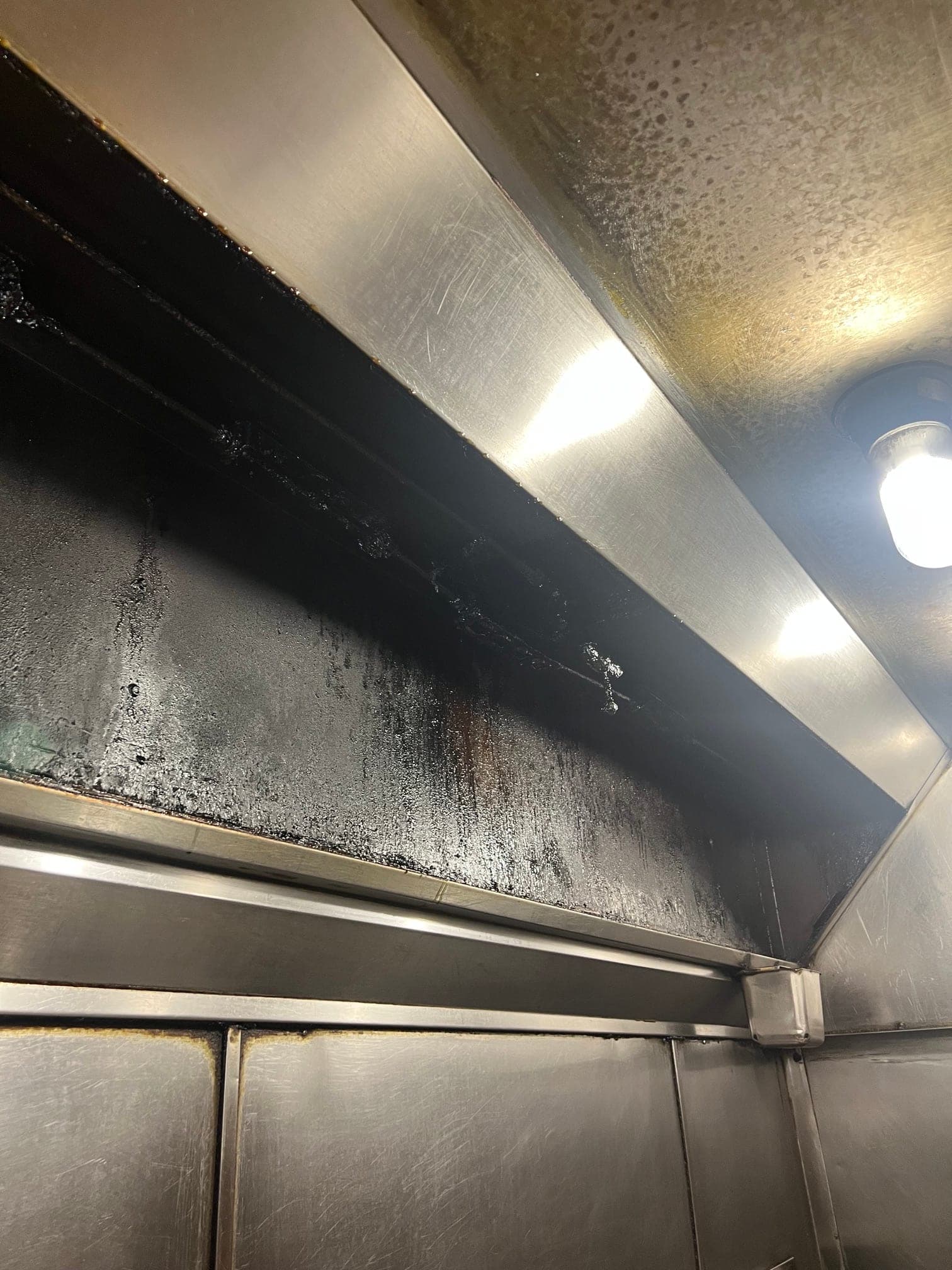 Grease buildup on the upper wall and detection hardware of a long kitchen hood