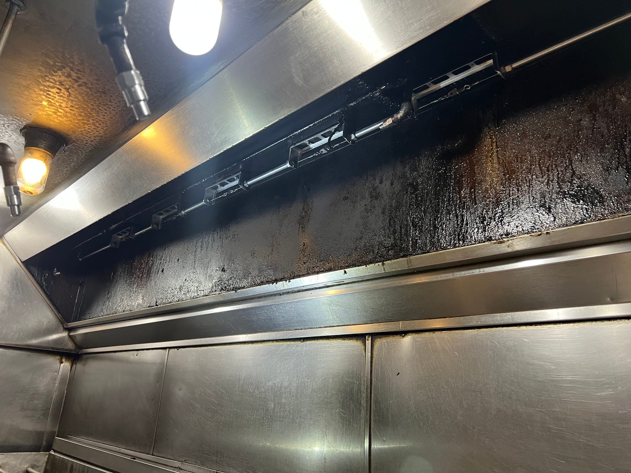 Row of detection brackets and nozzles along a grease-stained hood